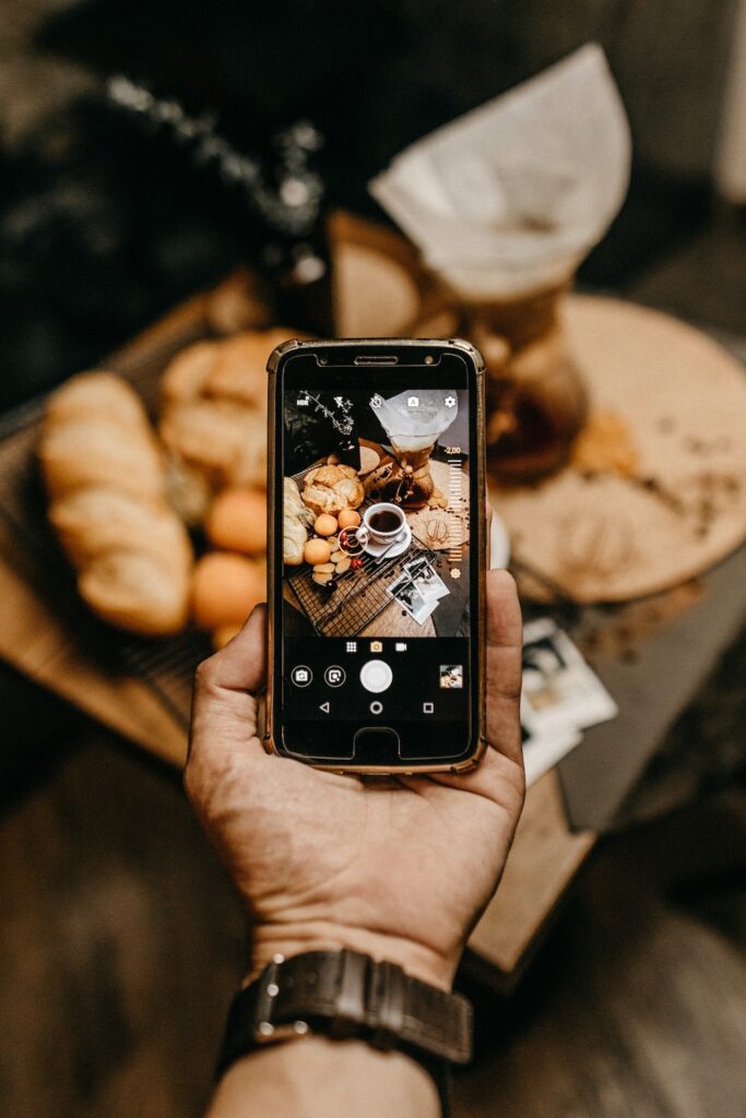 Cell phone taking a picture of coffee and pastries
